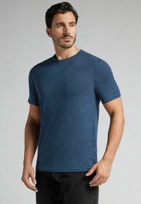 Pánské tričko s krátkým rukávem a kulatým výstřihem v námořnické modré barvě, vyrobené z měkké, texturované tkaniny. Má volný střih a minimální švy.