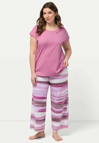 Rosa kortärmad t-shirt med broderi som säger "good vibes", kombinerad med vida pyjamabyxor med ett horisontellt randigt mönster i rosa, vitt och grått.