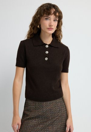 Bruine poloshirt met korte mouwen en een kraag, voorzien van drie decoratieve bloemvormige knopen en een getailleerd ontwerp.
