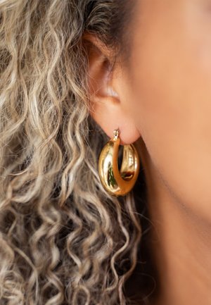 Boucles d'oreilles en or en forme de créoles avec une surface lisse et brillante et un design en spirale, présentant une finition polie et un fermoir sécurisé.