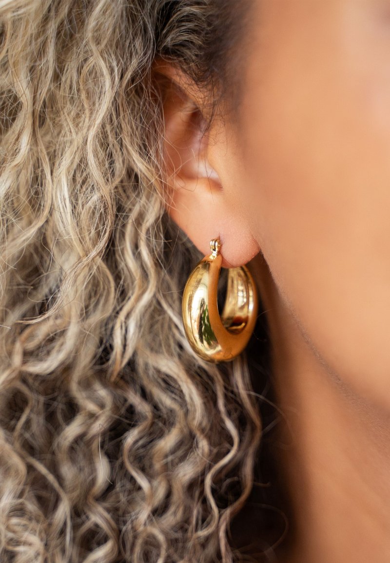 Boucles d'oreilles en or en forme de créoles avec une surface lisse et brillante et un design en spirale, présentant une finition polie et un fermoir sécurisé.