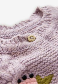 Lavendel gebreide stof met ribbelstructuur, voorzien van een kleine beige bloemetjesknop en gedeeltelijke bloemenborduring in roze, zwart en groen.