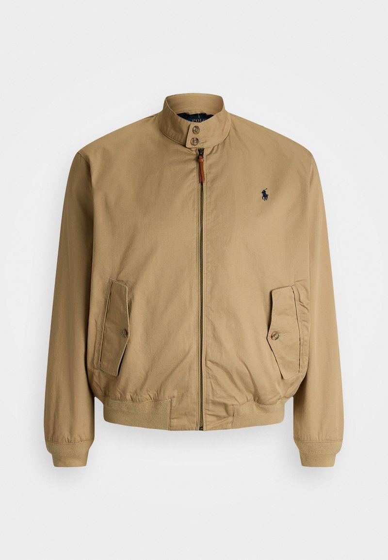 Lett og tynn jakke i beige med stående krage, frontglidelås, elastiske mansjetter og logo på venstre bryst. Har sidelommer og en glatt tekstur.