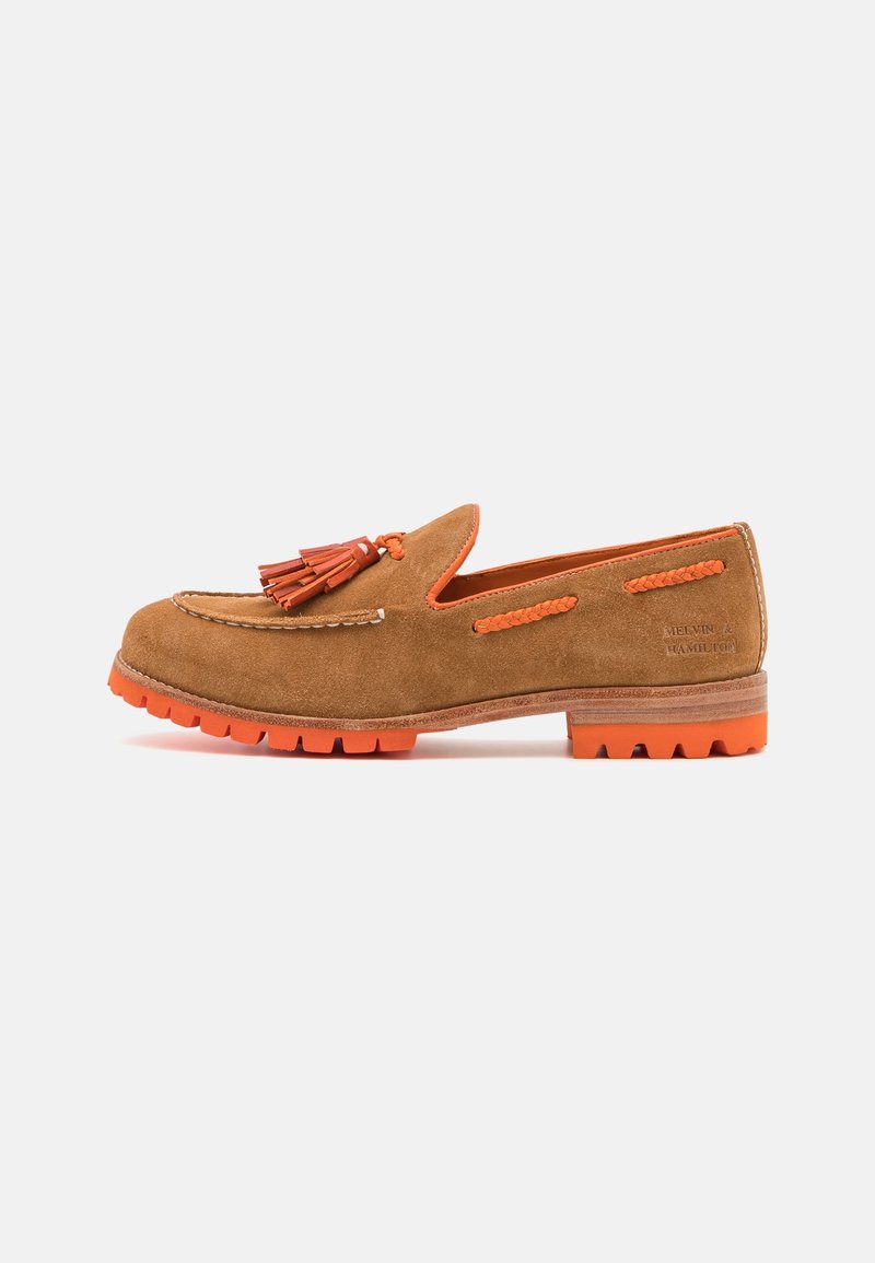 Mocassin en daim marron avec semelle en caoutchouc orange, accents tressés orange et pompons sur le dessus, vue de côté sur fond blanc.