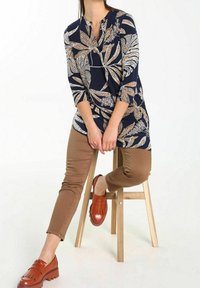 Granatowa koszula z białymi i złotymi wzorami liści, z rękawami o długości siedmiu ćwiartek i luźnym krojem, zestawiona z brązowymi spodniami i brązowymi mokasynami.