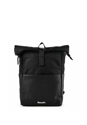 Sac à dos noir à rabat enroulable avec poche avant zippée, matériaux en tissu et similicuir, et logo "Bench." centré en bas à l'avant.