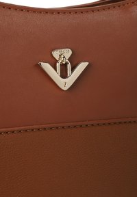 Brown leather bag featuring a gold V-shaped hardware accent and a triangular tag with the brand name VUCH. Textured surface with stitching detail.