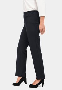 Zwarte, rechte broek met een elastische tailleband. Gladde, lichte stof. Gepaard met zwarte suède hoge hakken.