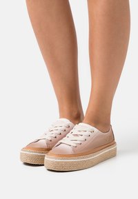 Růžové plátěné tenisky s tkanými juty podrážkami. Mají bílé tkaničky, zlaté očky a decentní logo na boku.