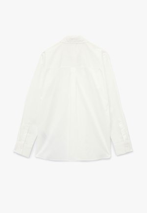 Camisa blanca de manga larga con cuello clásico, yugo trasero y puños abotonados. Textura suave y ajuste entallado.