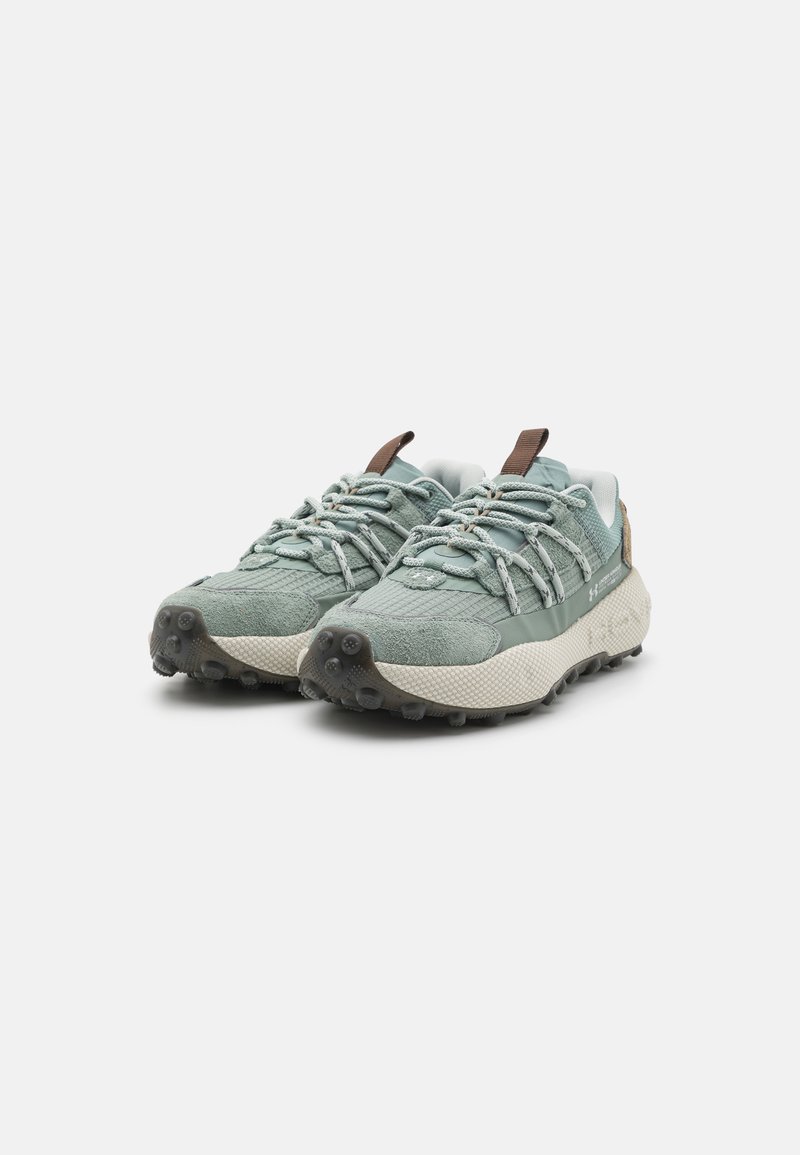 Chaussures de trail à lacets avec un dessus texturé vert menthe et des accents beige, dotées d'une semelle extérieure robuste pour l'adhérence et d'un soutien rembourré.