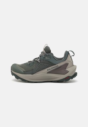 Trail-Schuhe in Grau und Grün, mit einem Obermaterial aus Mesh, strukturierten Überzügen und einer gummierten Laufsohle mit Profil für besseren Halt. Geometrische Akzente sind vorhanden.