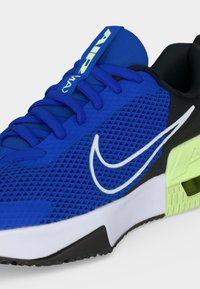 Μπλε αθλητικό παπούτσι Nike Air Max με λευκό λογότυπο, μπλε κορδόνια, μαύρη φτέρνα και λεπτομέρεια μαλακής σόλας σε ανοιχτό πράσινο.