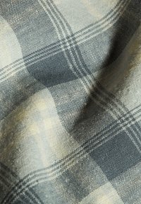 Katoenen plaidstof met een grijs, marineblauw en crème kleurenschema, met een geweven textuur, die een close-up van het patroon en de vezels toont.