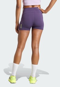 Paarse sportshorts met een hoge tailleband, met een ADIZERO-logo in neon geel aan de zijkant. Gladde, rekbare stof met minimale details.