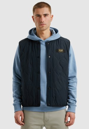 Navy quilted vest with buttons, featuring a textured pattern. Worn over a light blue hoodie, displayed on a neutral background.