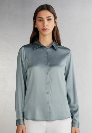Licht teal satijnen blouse met een knoopsluiting aan de voorkant, lange mouwen en een klassieke kraag. Beschikt over een soepele textuur en een getailleerde pasvorm.