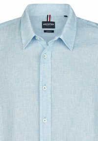 lichtblauw overhemd met knopen, gemaakt van textuurstof met een moderne pasvorm, voorzien van een pointed collar en witte knopen. Etiket: Hechter Paris.