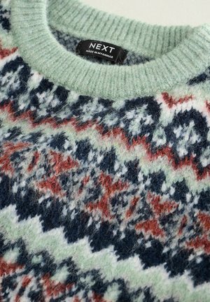 Strickpullover mit einem gerippten grünen Rundhalsauschnitt, der ein gemustertes Design in Marineblau, Weiß und Rostfarben zeigt; weiche Textur ist offensichtlich.