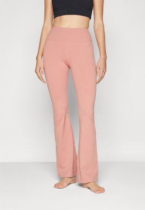 Pantalons de sport évasés en tissu doux et rose clair avec une texture lisse. Design taille haute avec un petit logo sur la hanche.