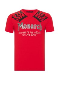 Rotes kurzärmliges T-Shirt mit V-Ausschnitt, metallischem Grafiktext "Monarch" und einem Krondesign mit filigranen Details auf den Schultern.