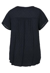 Blouse bleu marine à manches courtes avec motif subtil en points texturés, coupe ample et petit détail découpé aux bords des manches.