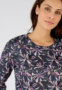 Top a maniche lunghe in navy con un motivo floreale che presenta fiori rosa, viola e crema. Il materiale sembra avere una texture e presenta un collo rotondo.