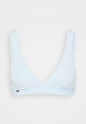 Vaaleansininen langaton kolmio-rintsikka, jossa on leveät olkaimet, ribbattu pinta ja joustava nauha, jossa on pieni Lacoste-logo.