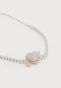 Ασημένιο κολιέ τένις με διάφανα πετράδια και γουράκι με πασχαλίτσα διακοσμημένη με κρύσταλλα και λεπτομέρειες σε χρυσό χρώμα.