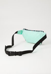 Sac banane vert menthe en tissu, doté d'une sangle noire ajustable et d'une fermeture éclair. Texture lisse avec une forme triangulaire.