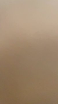 Beige or light brown surface with a smooth texture, possibly a wall or fabric, lacking distinct patterns or notable features.