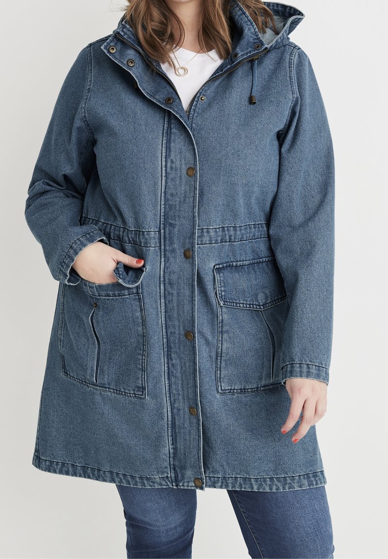 Denim parka bunda ve středně modré barvě, s kapucí, předními knoflíky, dvěma velkými předními kapsami a volným střihem s dlouhými rukávy.
