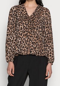 Leopardi-kuosiset puserot, joissa on röyhelökaulus, pitkät hihat ja poimutettu helma. Kankaan pinta on sileä ja kevyt, ja siinä on ruskeita ja mustia sävyjä.