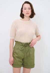 Maglione beige a maglia con un motivo testurizzato abbinato a pantaloni corti verde oliva con vita arricciata e cordoncino, orli risvoltati.