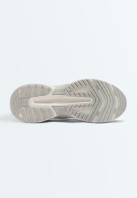 Semelle de chaussure avec motif en relief aux nuances de beige et gris, conçue pour l'adhérence et la durabilité, sur un fond clair uni.