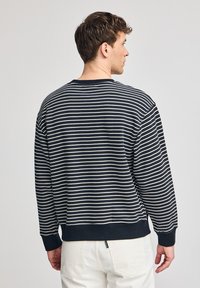 Mörkblå randig sweatshirt med krämfärgade horisontella ränder, ribbade mudd och midja. Har en rund halsringning och avslappnad passform, tillverkad av mjukt tyg.