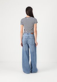 Gestreepte t-shirt in marineblauw en wit, gecombineerd met lichtblauwe wijdjesjeans. Katoen materiaal, casual ontwerp, met een label aan de achterkant.