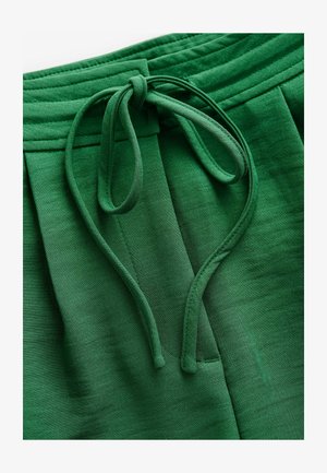 Pantaloni plisați verzi cu o textură netedă, având un șnur din material la talie și accente de elastic la adunare.