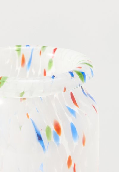 Vase en verre clair avec un bord évasé, décoré de taches colorées dispersées en bleu, rouge, vert et orange sur un fond blanc.