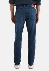 Jeans blu scuro in denim, con design a gamba dritta, due tasche posteriori e una patch in pelle marrone ai fianchi.