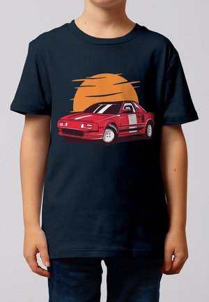 Enfant portant un t-shirt bleu foncé avec un graphique de voiture de sport rouge devant un soleil stylisé orange.
