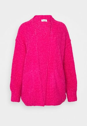 Lyserød chunky strikket åben-front cardigan med lange ærmer og afslappet pasform på ensfarvet baggrund.