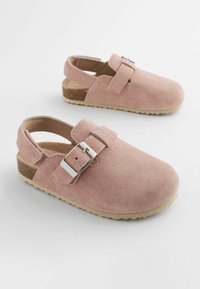 Sandales en cuir suédé rose clair avec un bout fermé, une sangle réglable, une boucle en argent et une semelle en caoutchouc texturé.