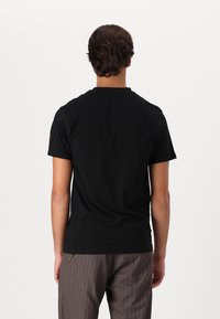 Camisetă din bumbac neagră, cu mâneci scurte, de tip crew, și o croială lejeră. Materialul pare neted și ușor.