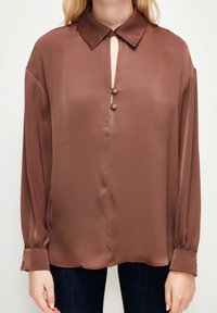 Brun silkebluse med krave, nøglehuludskæring og detalje med tre knapper, med lange ærmer med knapfunktion og glat tekstur.