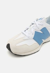 Baskets avec une tige en cuir blanc et des accents bleu clair. Embout en daim et semelle extérieure texturée. Lacets blancs. Forme arrondie.
