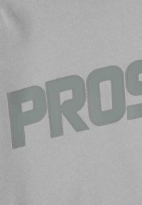 Szary dres z teksturowanej tkaniny z dużym, wyraźnym napisem "PRO" w nieco ciemniejszym odcieniu szarości.