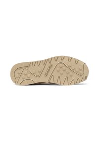 Svetlohnedá podrážka tenisiek s textúrovaným, vlnitým vzorom a kruhovými gripmi. Na strednej časti je značka Reebok.
