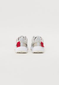 Leichte Sneakers mit einem Obermaterial aus weißem und grauem Mesh, gepolstertem Kragen, roten Akzenten und einer strukturierten Gummisohle. Minimalistisches Design, sportlicher Stil.