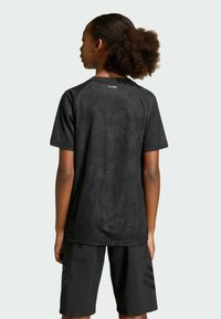 Black short-sleeve shirt with a textured, tonal pattern, paired with black shorts featuring side stripes. Relaxed fit for comfort.
